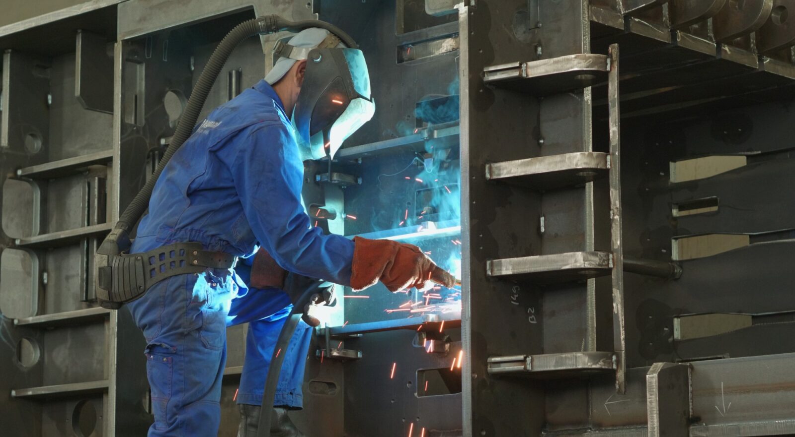 An engineer is welding a frame of a baler